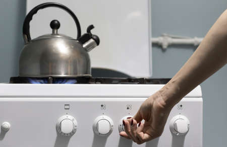 a person adds gas on the stove where the kettle is. High quality photoの写真素材