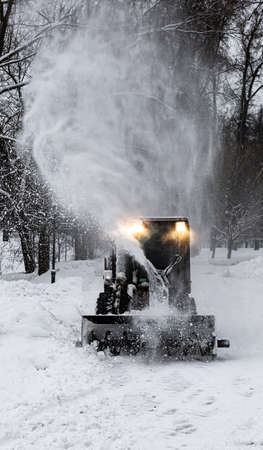 Moscow, Russia - December 07, 2021: small tractor removing snow after snowfall in winter. High quality photoのeditorial素材