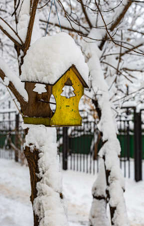 a small bird house covered with snow hangs from a tree in winter. High quality photoの写真素材