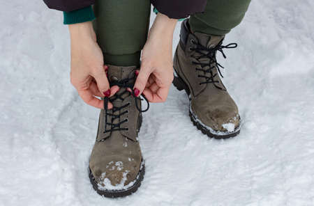 woman tying shoelaces on a boot outdoors in winter. High quality photo