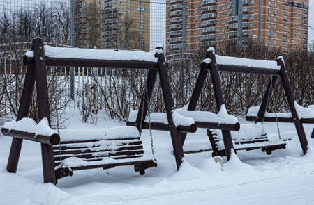 wooden multi-seat swing on the playground in the winter park. High quality photoの写真素材