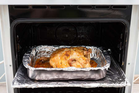 fried chicken carcass lies on a tray in an open oven. high quality photoの写真素材