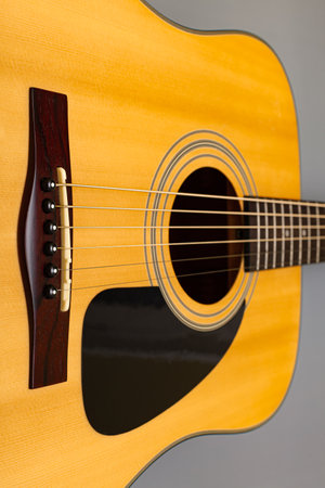 upper soundboard of an acoustic yellow guitar close-up on a gray background. high quality photo