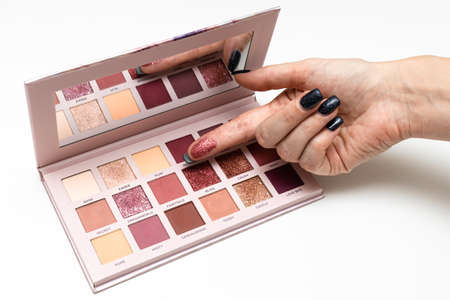 female finger touching paint in eyeshadow palette. high quality photo