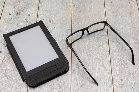a table on which lies an electronic book next to it a glasses. high quality photoの写真素材