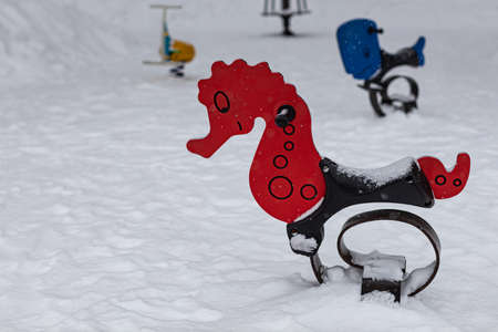 children's swing in the form of a seahorse on the playground in winter. high quality photoの写真素材