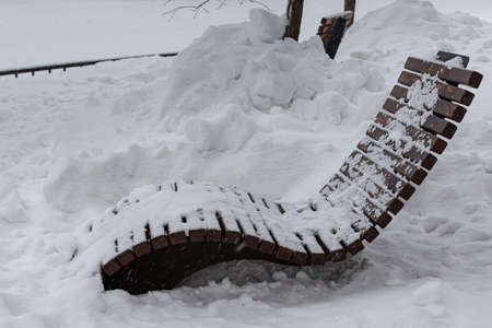 wooden chaise longue in a winter park during a snowfall. high quality photoの写真素材