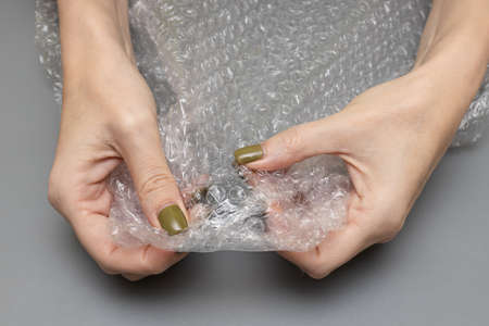 woman bursting wrap in her hands on a gray background. high quality photo