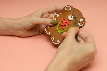 female hand decorates a gingerbread with tweezers. high quality photoの写真素材