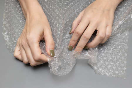 woman bursting wrap in her hands on a gray background. high quality photo