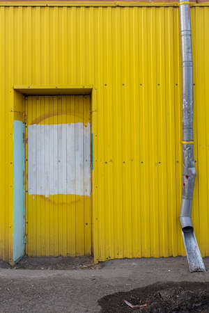 blocked entrance to a yellow colored building next to a drain pipe