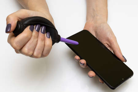 female hand using a pear removes dust from the smartphone
