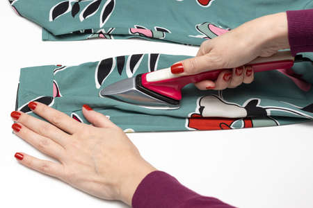 woman ironing a colored women's blouse with a miniature iron. high quality photo