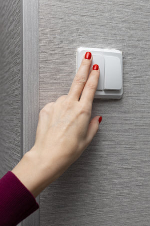 female hand presses the wall switch button. high quality photo