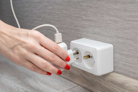 woman's hand inserts charging into the socket. high quality photo