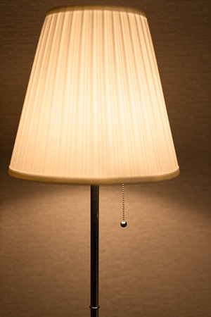 a floor lamp with a lampshade stands against the background of a wall. high quality photoの写真素材