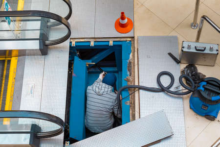 worker repairing escalator mechanism. high quality photoの写真素材