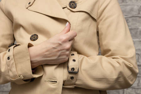 a woman in a raincoat put her hand in her bosom. high quality photo