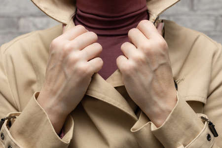 a woman in a raincoat puts her hand on the lapels of her collarの写真素材