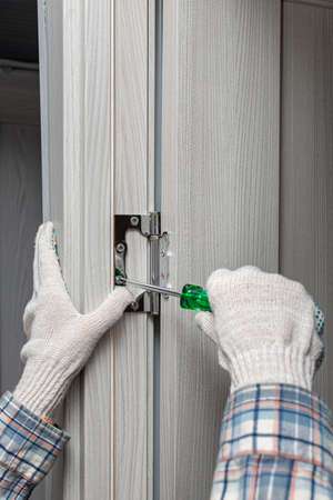 man screwing a door hinge with a screwdriver