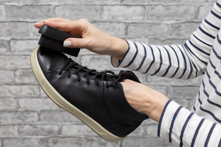 woman wiping her black shoes with a sponge. high quality photoの写真素材