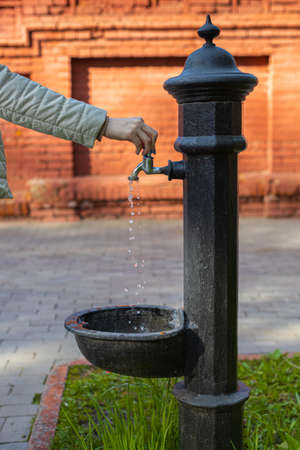 woman's hand opens the faucet of the water column on the street. high quality photoの写真素材
