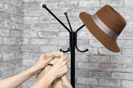 a woman hangs her coat on a hook on a hanger. high quality photoの写真素材
