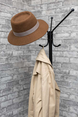 a hat and a raincoat hang on a metal floor hanger. high quality photoの写真素材