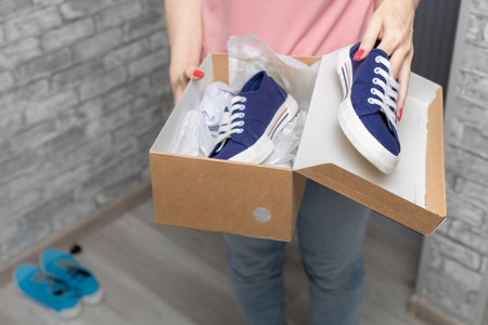 a woman takes new sneakers out of the box to try on. high quality photo