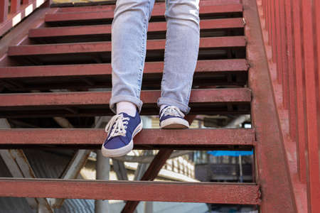 legs in blue jeans and blue sneakers descend the stairs. high quality photoの写真素材