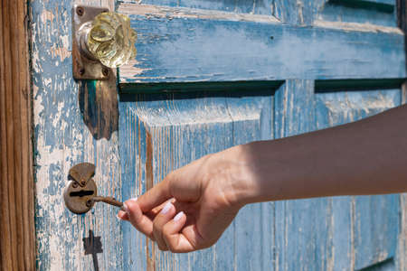 female hand opens the door lock with a rusty key. high quality photo
