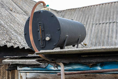 an old heating tank stands on the roof of a summer shower in the village. high quality photoの写真素材