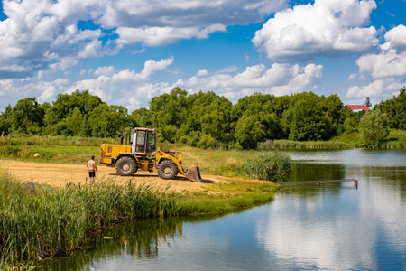 Ryazan, Russia - July 15, 2022: tractor rakes sand on the river beach in summer. high quality photoのeditorial素材