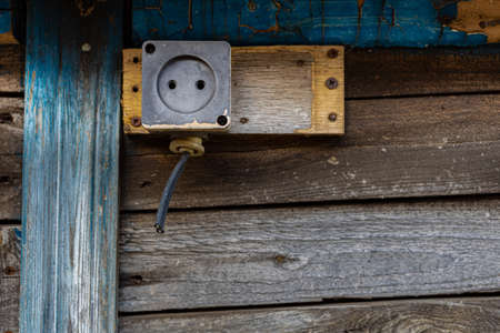 an old socket with a cut wire nailed to a wooden building. high quality photo