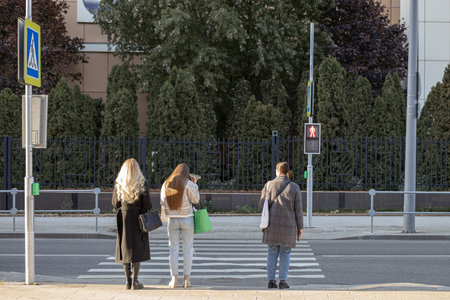 Moscow, Russia - October 18, 2022:woman standing in front of a crosswalk. people are crossing the roadのeditorial素材