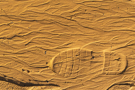 footprint of a boot tread on yellow sand. footprints in the sand