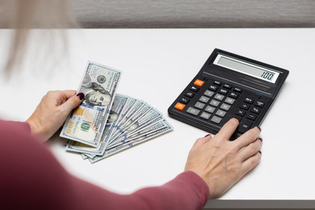 man presses a calculator button with his finger. man counting dollars. cash accounting.の写真素材