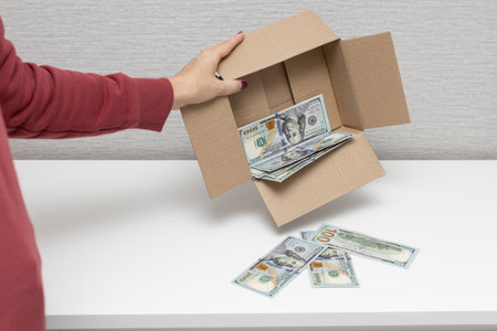 a man holds a box in which dollars. man shakes dollars out of the box. high quality photoの写真素材