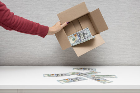 a man holds a box in which dollars. man shakes dollars out of the box. high quality photoの写真素材