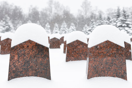 tombstone in a cemetery covered with snow in winter. monument in the cemetery. grave in the cemetery in winterの写真素材