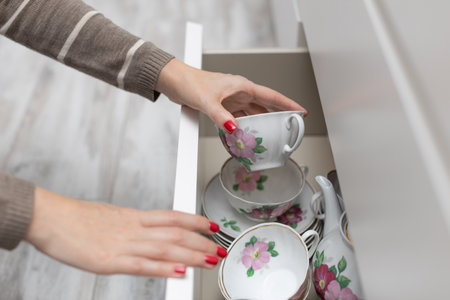 woman taking dishes out of the cupboard. man holding a mug. woman holding a cup. tea setの写真素材