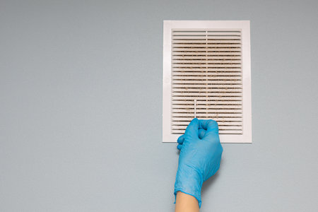 man checks the condition of the ventilation grill. home ventilation disinfection. high quality photoの写真素材