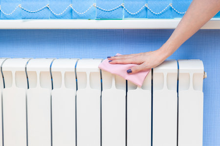 Woman removes dust from a heating radiator. woman cleaning the room. home heating radiator.の写真素材