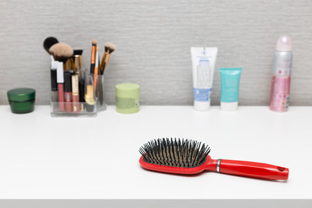 old used hairbrush on the table with cosmetics. an old comb with sticking hair lies on the table. old comb with hair.の写真素材