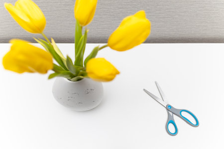 scissors lie near a vase of flowers. yellow tulips in a vaseの写真素材
