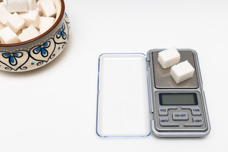a sugar cube lies on a small scale. sugar control. sugar cubes in a sugar bowl. healthy lifestyle....