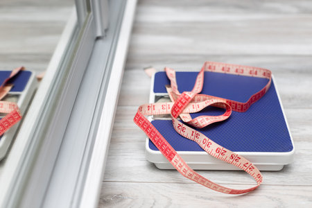 red measuring tape taken with a shallow depth of field. red measuring tape lies on the scales. diet and weight loss.の写真素材