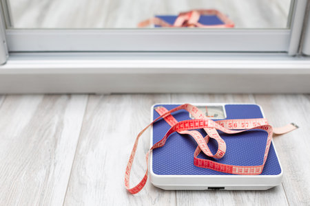 red measuring tape taken with a shallow depth of field. red measuring tape lies on the scales. diet and weight loss. high quality photoの写真素材