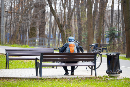Moscow, Russia - April 18, 2023: cyclist resting in the park on a bench. cyclist in the parkのeditorial素材