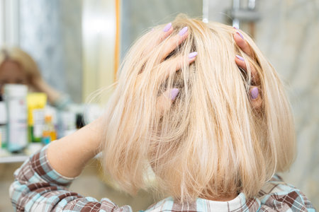 woman fixing her hair standing in front of a mirror. girl fixing her hairの写真素材